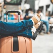 Lioton® Gel în călătorie, o persoană stă pe o bancă cu picioarele sprijinite deasupra unui rucsac.