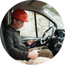 Lioton® Gel la locul de muncӑ, Bǎrbat purtând o cascӑ roșie, stând într-un camion de lucru, verificându-și telefonul